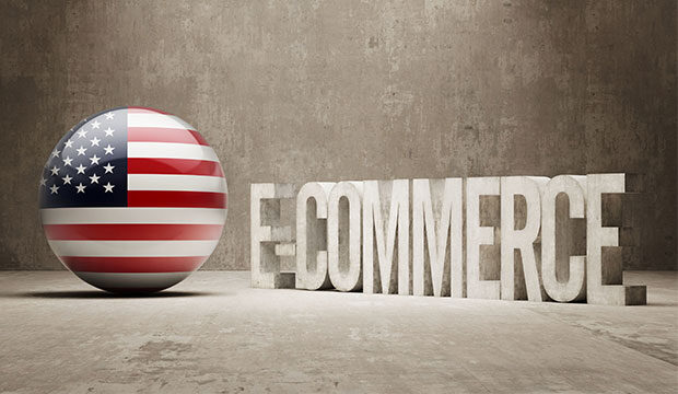 Concrete letters spelling E-COMMERCE next to a sphere painted as the US flag